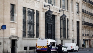 Police officials stand alongside police and private security vehicles outside The Bank of America building in the 8th arrondissement of Paris on March 28, 2026, following an apparent bomb attack attempt. (Photo by Sebastien Dupuy / AFP)