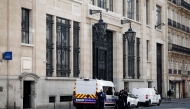Police officials stand alongside police and private security vehicles outside The Bank of America building in the 8th arrondissement of Paris on March 28, 2026, following an apparent bomb attack attempt. (Photo by Sebastien Dupuy / AFP)