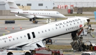 An executive jet taxis behind the Air Canada Express CRJ-900 that collided with a Port Authority fire truck at LaGuardia Airport in New York, after the airport resumed operations on March 23, 2026. Photo by TIMOTHY A. CLARY / AFP