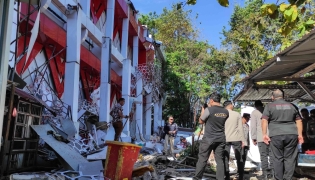 Police officers look at a building of the North Sumatra's National Sports Committee of Indonesia (KONI) damaged following a severe 7.4-magnitude offshore quake in Manado, North Sulawesi on April 2, 2026. (Photo by Tonny Rarung / AFP)