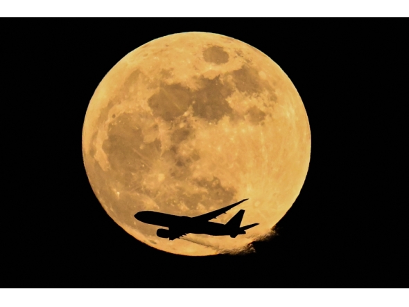 Air China cargo's airline Boeing 777-FFT aircraft flies past the April full moon in Frankfurt am Main, western Germany on April 1, 2026. (Photo by Kirill Kudryavtsev / AFP)