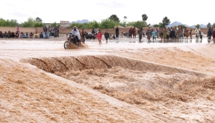 An Afghan motorist wades across a flooded road at Zawul district in Herat province on April 2, 2026. (Photo by Mohsen KARIMI / AFP)