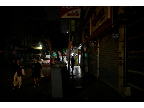 People walk past a closed cinema as shops close early under a government-ordered curfew aimed at reducing energy costs in downtown Cairo on April 2, 2026. Photo by KHALED DESOUKI / AFP