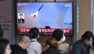 People watch a television screen showing a news broadcast with file footage of a North Korean missile test, at a train station in Seoul on April 8, 2026. North Korea fired multiple short-range ballistic missiles on April 8, south korea's military said, hours after reporting an 
