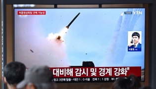 People watch a television screen showing a news broadcast with file footage of a North Korean missile test, at a train station in Seoul on April 19, 2026. Photo by Jung Yeon-je / AFP