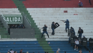 Fans of Cerro Porteno clash with police officers during the Paraguayan tournament football match between Olimpia and Cerro Porteno at the Defensores del Chaco stadium in Asuncion on April 19, 2026. (Photo by Daniel Duarte / AFP)