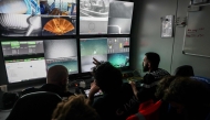 Pilots specializing in underwater robots from the French Navy, along with researchers, watch live feeds on screens showing the “ROV C 4000,” a remotely operated vehicle manufactured by the French company LD Travocean and designed for seabed exploration, during an archaeological mission on the wreck of the CAMARA 4 from the bridge of the (BSAA) Jason, off the coast of Ramatuel, in southeastern France, April 7, 2026. Photo by Thibaud MORITZ / AFP