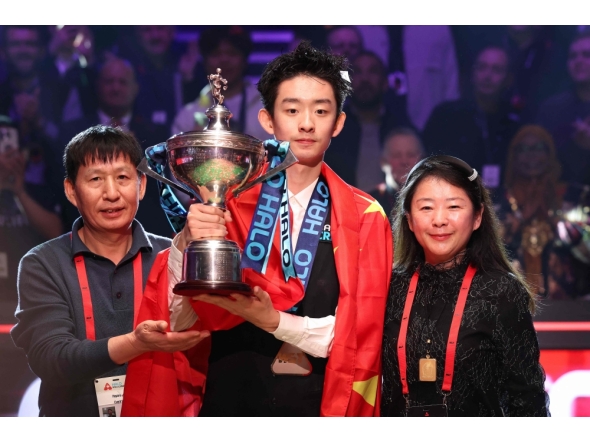 China's Wu Yize (C) holds the championship trophy as he poses with his parents during the awards ceremony after his victory over England's Shaun Murphy in the World Snooker Championship final round at The Crucible in Sheffield, northern England on May 4, 2026. (Photo by Darren Staples / AFP)