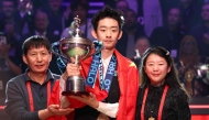 China's Wu Yize (C) holds the championship trophy as he poses with his parents during the awards ceremony after his victory over England's Shaun Murphy in the World Snooker Championship final round at The Crucible in Sheffield, northern England on May 4, 2026. (Photo by Darren Staples / AFP)