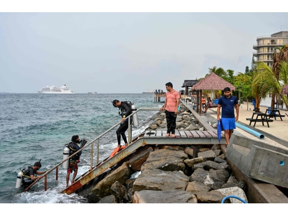 A tourist, along with guides, returns after an open-water diving session near Rasfannu Beach in Malé on May 15, 2026. Photo by Mohamed Afrah / AFP
