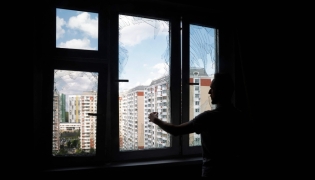 A local resident removes glass shards from a broken window in a residential building following an air attack in Krasnogorsk, Moscow region on May 17, 2026. (Photo by Tatyana Makeyeva / AFP)