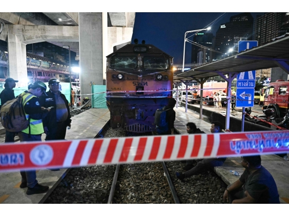 (Files) Officials stand next to the front of a train that collided with a bus underneath Makkasan Airport Rail station in Bangkok on May 16, 2026. (Photo by Lillian Suwanrumpha / AFP)
 