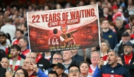 (FILES) A hopeful Arsenal fan holds up a banner reading '22 years of waiting' ends this season, during the English Premier League football match between Arsenal and Burnley at the Emirates Stadium in London on May 18, 2026. (Photo by Glyn KIRK / AFP)