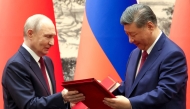 In this pool photograph distributed by the Russian state agency Sputnik, Russia's President Vladimir Putin and China's President Xi Jinping exchange documents during a signing ceremony following their talks in Beijing on May 20, 2026. (Photo by Alexander Kazakov / POOL / AFP)