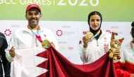 Qatar's Saeed Abu Sharib and Maytha Al-Binali celebrate on the podium after winning the mixed team trap gold. 