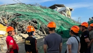 This handout photo taken and released on May 24, 2026 via the Facebook page of the Angeles City Public Information Office shows rescuers standing next to a collapsed building in Angeles City in Pampanga province. (Photo by Handout / Angeles City Public Information Office / AFP) 