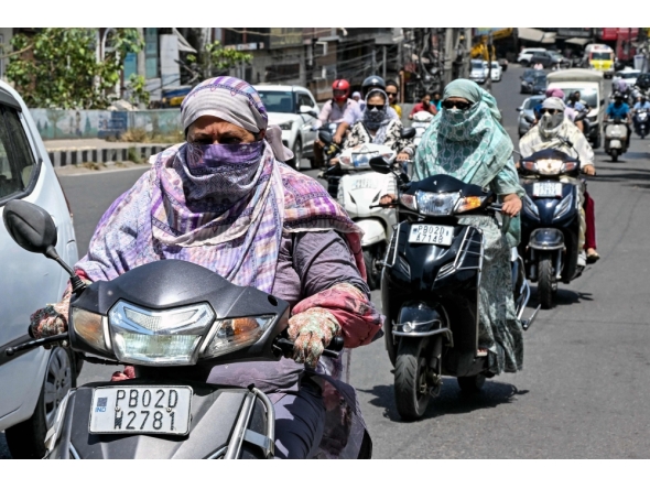 Commuters with their faces covered with cloth ride along a street on a hot summer afternoon in Amritsar on May 23, 2026. (Photo by Narinder NANU / AFP)
 