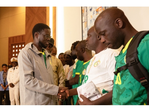 President of Senegal Bassirou Diomaye Faye (L) shakes hands with Senegalese supporters who were granted a royal pardon in Morocco as they arrive at Blaise Diagne International Airport in Ndiass, Senegal (Photo by Seyllou / AFP)