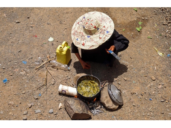 Displaced Yemeni woman Saeedah Mohammed boils tree leaves to feed her grand-children outside their makeshift tent in the Al-Manij displacement camp, near the city of Taez in Yemen's southwest, on May 21, 2026. (Photo by Ahmed al-Basha / AFP)