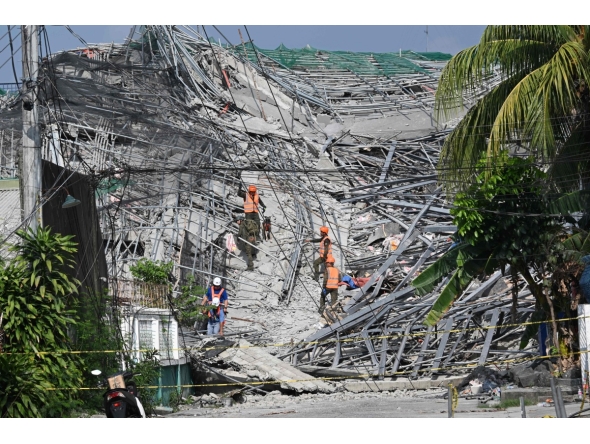Military personnel with a working dog conduct search and rescue operations at a collapsed building in Angeles City, Pampanga province, north of Manila on May 25, 2026. Photo by Ted ALJIBE / AFP