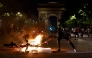 A member of the public holds an object to a burning bicycle on the Avenue de la Grande Armee during gatherings after PSG won the UEFA Champions League final between Paris Saint-Germain (PSG) and Arsenal FC played in Budapest (Photo by Kenzo Tribouillard / AFP)