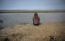 A resident affected by the Lapindo mudflow sits on the embankment in the mud volcano area, marking 20 years since a gas exploration accident triggered a mud flow that inundated more than a dozen villages and permanently displaced tens of thousands of people in Porong, Sidoarjo, East Java province on May 29, 2026. (Photo by JUNI KRISWANTO / AFP)