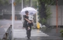 A woman holding her child walks through heavy rain brought by severe tropical storm Jangmi in Tokyo on June 3, 2026. (Photo by Yuichi Yamazaki / AFP)