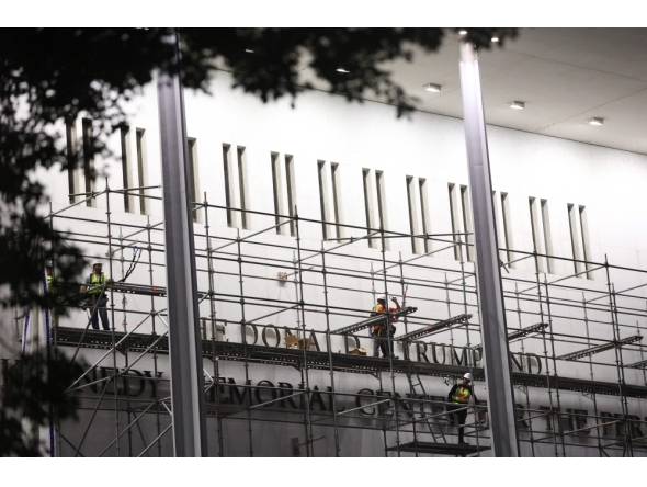 Workers build scaffolding near the signage for the 