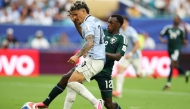 Uruguay's midfielder #20 Maximiliano Araujo and Saudi Arabia's defender #12 Saud Abdulhamid fight for the ball during the 2026 World Cup Group H football match between Saudi Arabia and Uruguay at the Miami Stadium in Miami Gardens on June 15, 2026. (Photo by PATRICIA DE MELO MOREIRA / AFP)
