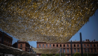 People walk through the Capitole square covered by an installation to provide shade, in Toulouse on June 19, 2026. Photo by Lionel BONAVENTURE / AFP