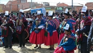 Indigenous people wearing signs reading 