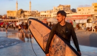 Palestinian surfer Tahseen Abu Assi, 23, takes his surfboard out into the Mediterranean sea off a beach in Gaza City on June 21, 2026. (Photo by Omar Al-Qattaa / AFP)