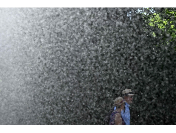 A man and woman walk past the water stream of a sprinkler system at the WTA 500 Bad Homburg Open tennis tournament in Bad Homburg, western Germany on June 25, 2026. (Photo by Kirill KUDRYAVTSEV / AFP)
 