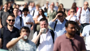 Commuters walk in the sun as they cross London Bridge, during a heatwave, in central London on June 24, 2026. (Photo by Toby Shepheard / AFP)