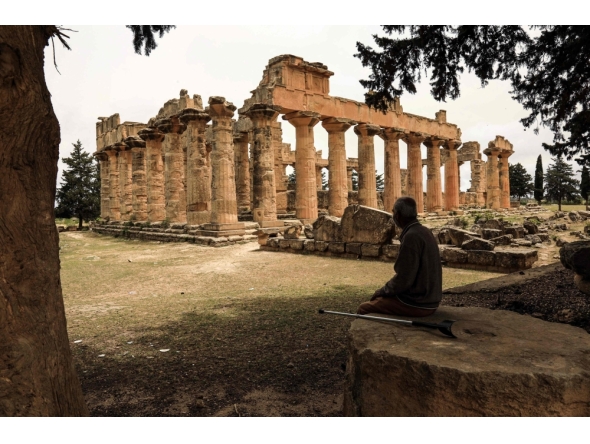 (Files) A man sits in the shade in front of the Temple of Zeus at the archaeological site of Cyrene, near the town of Shahat on Libya's northeastern Mediterranean coast, on May 18, 2026. (Photo by Abdullah Doma / AFP)
