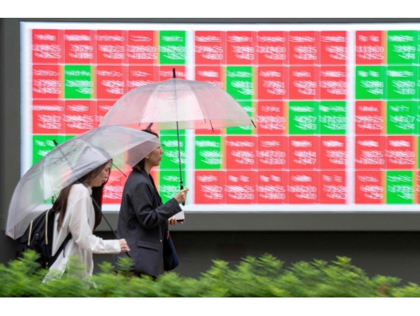 Pedestrians walk past an electronic quotation board displaying the Nikkei 225 stock prices on the Tokyo Stock Exchange along a street in Tokyo on June 25, 2026. (Photo by Kazuhiro NOGI / AFP)
