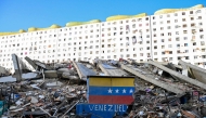 A Venezuelan flag is seen painted on a damaged wall amid the rubble of a collapsed building following earthquakes in Caraballeda, La Guaira state, Venezuela, on June 26, 2026. (Photo by Maryorin Mendez / AFP)