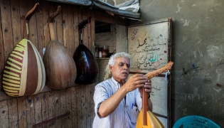 Displaced Palestinian craftsman Suhail Abu Shawish tunes a Oud musical instrument at his makeshift workshop in the Nuseirat camp for Palestinian refugees in the central Gaza Strip on June 23, 2026. (Photo by Eyad Baba / AFP)