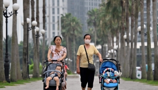 This photo taken on June 29, 2026, shows women pushing strollers with children along a sidewalk in Hanoi. Photo by Nhac Nguyen / AFP

