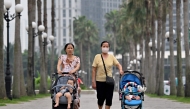 This photo taken on June 29, 2026, shows women pushing strollers with children along a sidewalk in Hanoi. Photo by Nhac Nguyen / AFP

