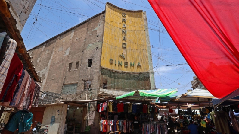 Street vendors gather outside the faded facade of the Granada Cinema, an early 1940s landmark, in the Bab al-Sharqi district of central Baghdad on May 26, 2026. (Photo by Ahmad Al-Rubaye/ AFP)