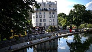 Files: People sit along the canal Saint-Martin in Paris on May 17, 2022. Photo by Christophe Archambault / AFP