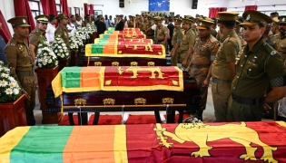Security personnel pay tribute as they stand next to coffins of seven guards killed during Negombo prison riot in Colombo July 8, 2026. (Photo by Ishara S. Kodikara / AFP)