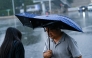 A man holding an umbrella walks along a road on a rainy day in Beijing on July 10, 2026. (Photo by WANG Zhao / AFP)