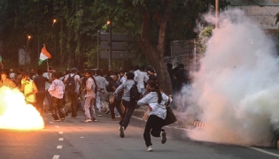 Rapid Action Force (RAF) personnel fire tear gas shells to disperse supporters of the Cockroach Janta Party (CJP) during a protest demanding the resignation of India's Education Minister Dharmendra Pradhan over alleged NEET exam irregularities in New Delhi on July 20, 2026. (Photo by Arun SANKAR / AFP)