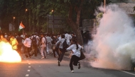 Rapid Action Force (RAF) personnel fire tear gas shells to disperse supporters of the Cockroach Janta Party (CJP) during a protest demanding the resignation of India's Education Minister Dharmendra Pradhan over alleged NEET exam irregularities in New Delhi on July 20, 2026. (Photo by Arun SANKAR / AFP)