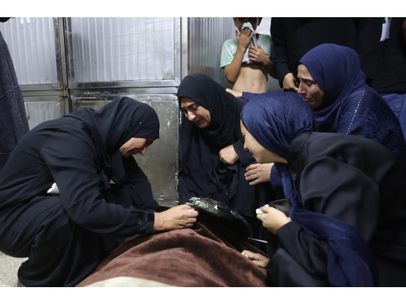 Mourners weep over the body of one of the Palestinian who died after an Israeli airstrike targeted a residential apartment in the Sabra neighborhood of Gaza City on July 21, 2026. (Photo by Omar AL-QATTAA / AFP)