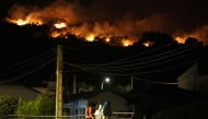 Residents watch the flames on hill crests as firefighters battle a wildfire in Cebreros area, near Avila, 80 kms west of Madrid at night on July 24, 2026. (Photo by Cesar MANSO / AFP)
