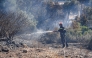 A firefighter uses a waterhose as he works to battle a wildfire, south of Rethymno in the Greek island of Crete on July 30, 2026.(Photo by Costas METAXAKIS / AFP)