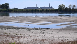 :The dried-up Danube riverbed is pictured with the Paks power plant at the background, near Dunaszentbenedek, close to Paks town on July 31, 2026. (Photo by Attila KISBENEDEK / AFP)